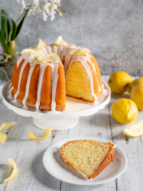 Ciambella al limone con glassa bianca colante e fettina tagliata che mostra la mollica soffice