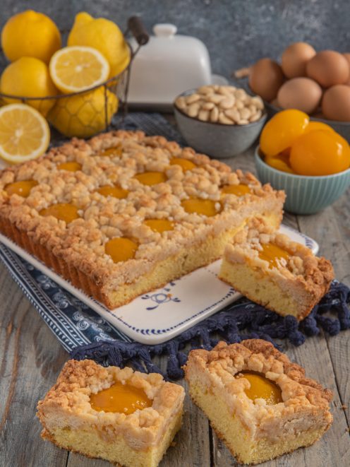 Crumble cake alle pesche con streusel dorato e fette tagliate che mostrano l'interno soffice