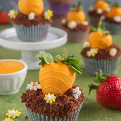 Cupcake carotina al cioccolato con fragola glassata arancione e briciole di biscotto