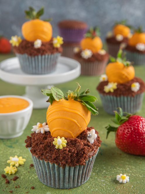 Cupcake carotina al cioccolato con fragola glassata arancione e briciole di biscotto