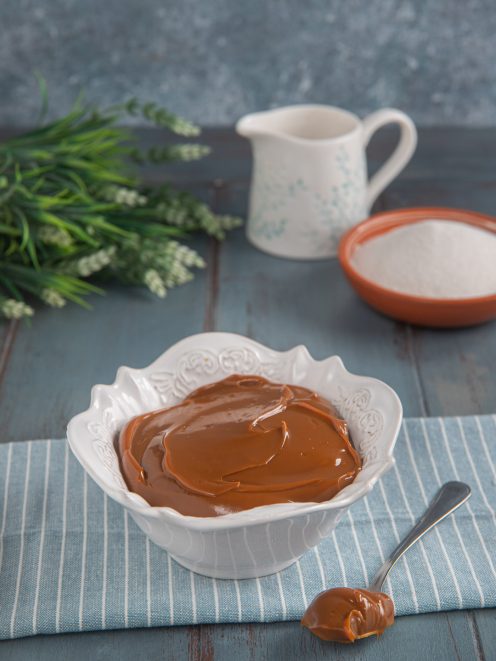 Dulce de leche cremoso e lucido servito in una ciotola, con un cucchiaio a lato