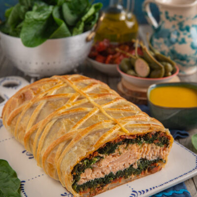 Filetto di salmone in crosta sfogliata tagliato a meta, con ripieno di spinaci e pomodorini secchi
