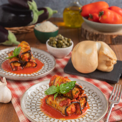 Involtini di melanzane alla pugliese in salsa di pomodoro, guarniti con foglie di basilico fresco