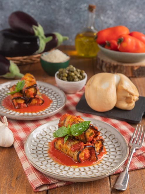 Involtini di melanzane alla pugliese in salsa di pomodoro, guarniti con foglie di basilico fresco