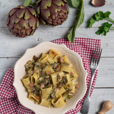 Pasta con carciofi, pancetta e prezzemolo servita in un piatto fondo
