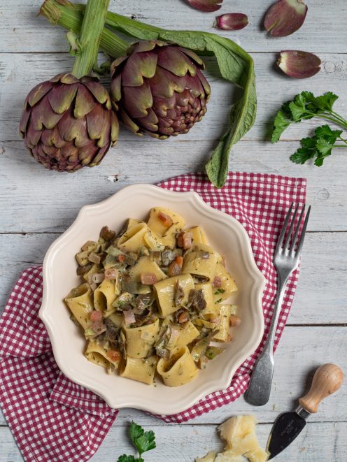 Pasta con carciofi, pancetta e prezzemolo servita in un piatto fondo