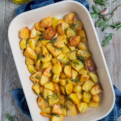 Patate al forno dorate a tocchetti con rametti di rosmarino fresco