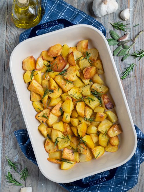 Patate al forno dorate a tocchetti con rametti di rosmarino fresco