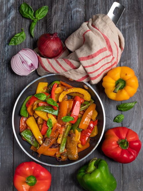 Peperoni in padella saltati con cipolla rossa e foglie di basilico fresco