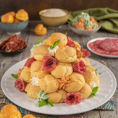Profiterole salato a torre con bignè farciti, salame arrotolato e crema alle erbe