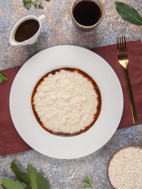 Risotto alla Bergese cremoso al centro del piatto con bordo di riduzione al vino rosso