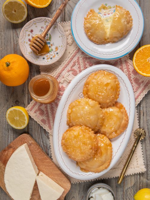 Seadas fritte glassate con miele, ripiene di formaggio, servite con arance e limoni