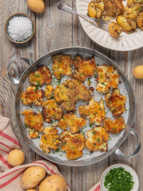 Smashed potatoes dorate e croccanti in teglia, guarnite con erba cipollina tritata