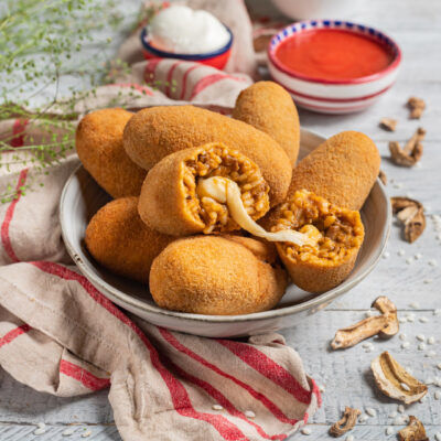 Supplì al telefono impanati e fritti, tagliati a metà con filo di mozzarella filante e ripieno di riso