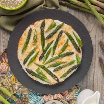 Torta di riso e asparagi gratinata con besciamella dorata e punte di asparagi verdi in superficie