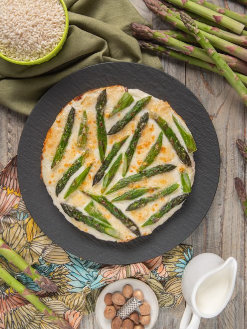 Torta di riso e asparagi gratinata con besciamella dorata e punte di asparagi verdi in superficie