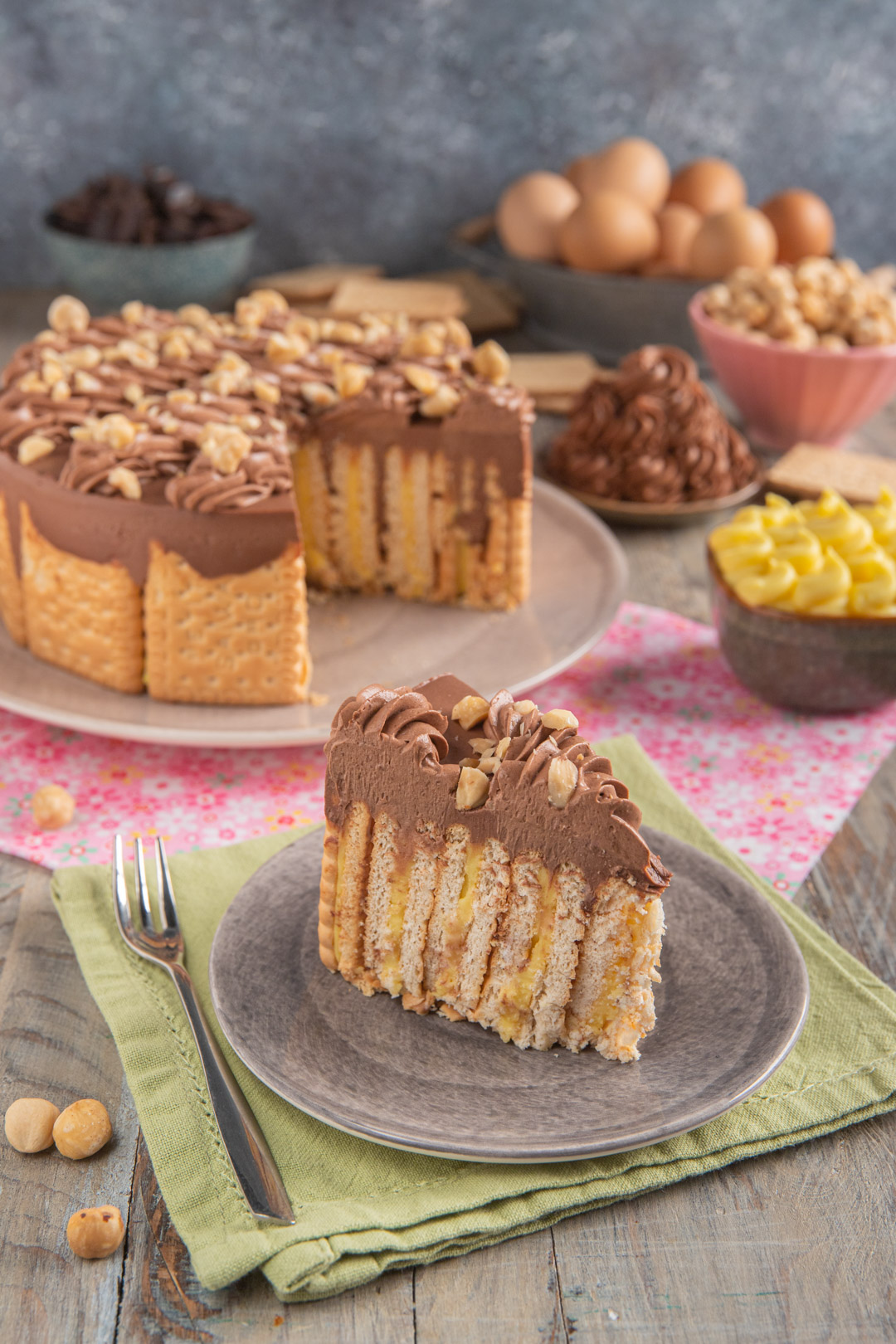 Fetta di torta fredda di biscotti secchi con crema al cioccolato, crema pasticciera e granella di nocciole