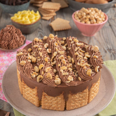 Torta fredda di biscotti secchi con bordo di frollini, crema al cioccolato e granella di nocciole