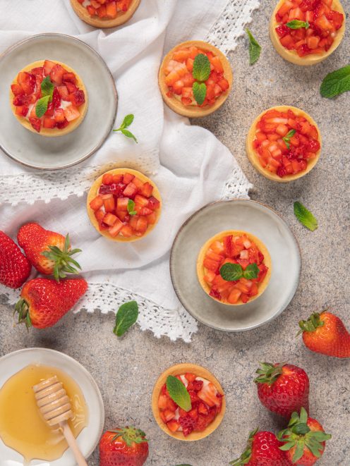 Tortine con crema al miele e fragole a cubetti, guarnite con foglioline di menta fresca