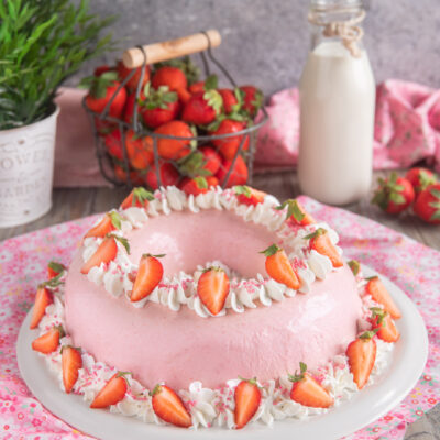 Bavarese alle fragole a ciambella decorata con ciuffi di panna e fragole fresche tagliate