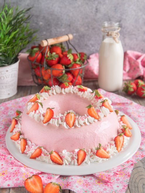 Bavarese alle fragole a ciambella decorata con ciuffi di panna e fragole fresche tagliate