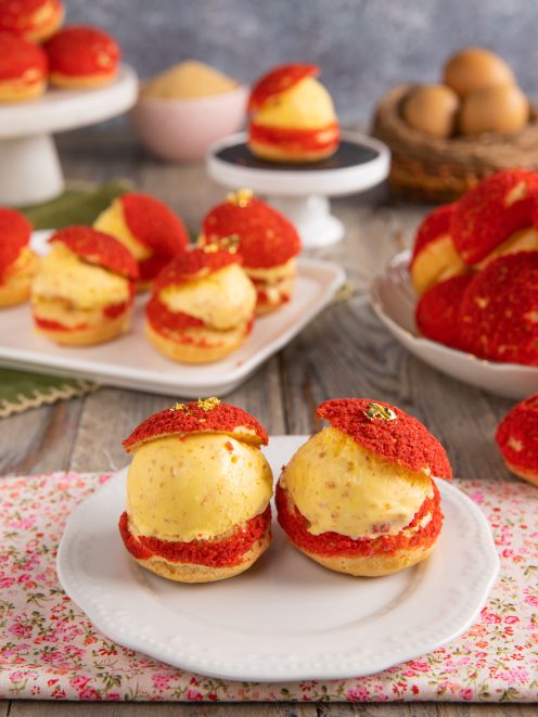 Bignè craquelin farciti con gelato cremoso e decorati con lamina d'oro su piattino da dessert