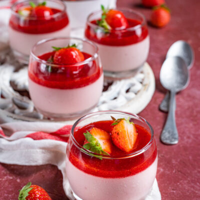 Cremoso alla fragola in bicchieri con coulis rosso e fragole fresche a decorare