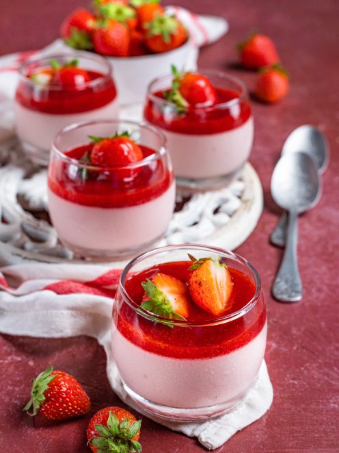 Cremoso alla fragola in bicchieri con coulis rosso e fragole fresche a decorare