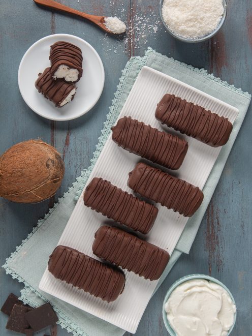 Gelatini al cocco e cioccolato allineati su un tagliere, con uno tagliato a mostrare il ripieno cremoso