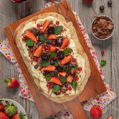 Pinsa romana dolce farcita con crema, fragole, mirtilli, more e scaglie di cioccolato
