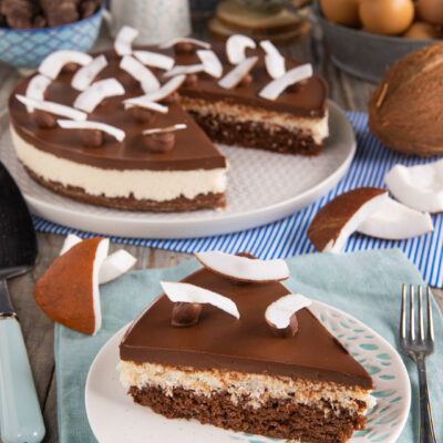 Torta cocco e cioccolato con strati di pan di spagna, crema al cocco e glassa, guarnita con scaglie di cocco fresco