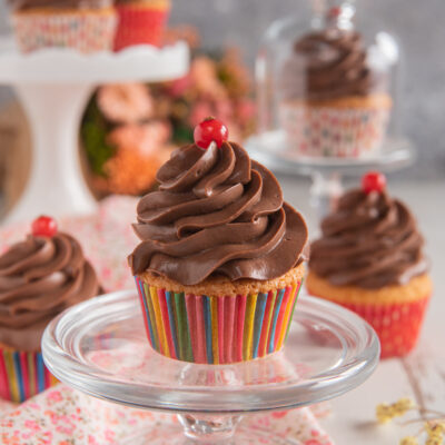 Cupcakes con frosting al cioccolato a spirale e una bacca rossa sulla sommità