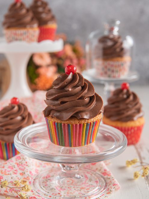 Cupcakes con frosting al cioccolato a spirale e una bacca rossa sulla sommità