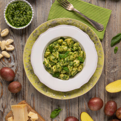 Gnocchi al pesto conditi generosamente con basilico fresco, serviti con parmigiano e pinoli