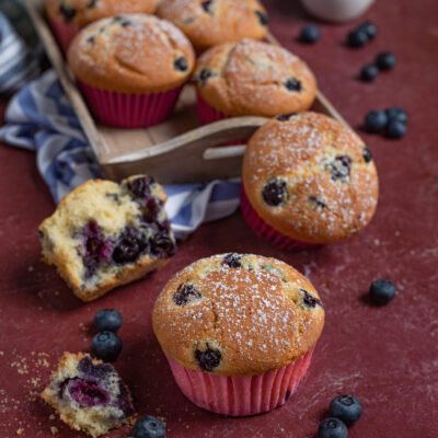 Muffin ai mirtilli spolverati di zucchero a velo, con uno aperto che mostra l'interno soffice