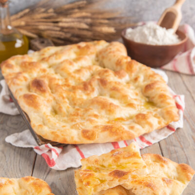 Pizza bianca romana soffice con superficie dorata e lucida di olio, tagliata in pezzi