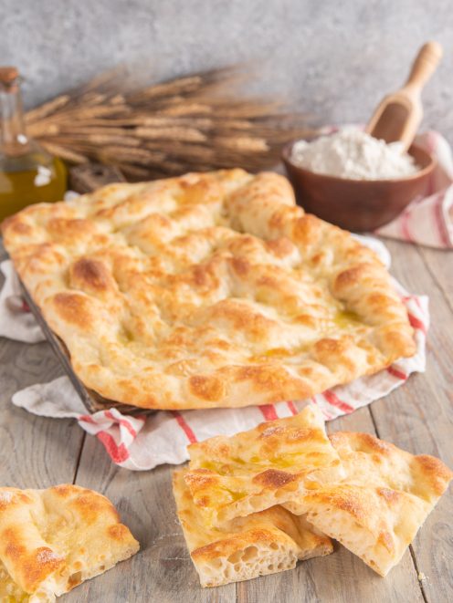 Pizza bianca romana soffice con superficie dorata e lucida di olio, tagliata in pezzi