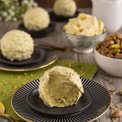 Semifreddo al pistacchio con copertura di cioccolato bianco e granella, tagliato per mostrare il cuore verde