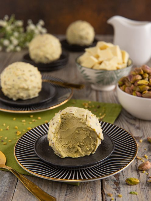 Semifreddo al pistacchio con copertura di cioccolato bianco e granella, tagliato per mostrare il cuore verde