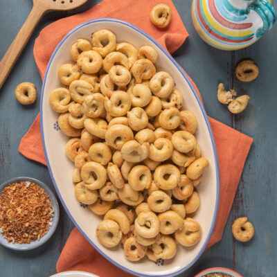 Taralli pugliesi dorati e croccanti serviti in abbondanza su un vassoio ovale
