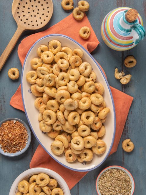 Taralli pugliesi dorati e croccanti serviti in abbondanza su un vassoio ovale