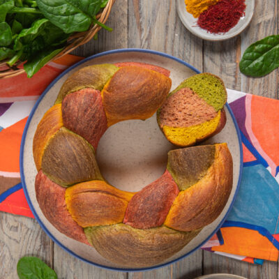 Treccia tricolore a corona colorata con curcuma, spinaci e barbabietola, tagliata a fette