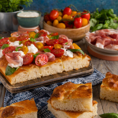 Focaccia ad alta idratazione farcita con stracciatella, pomodorini colorati, prosciutto crudo e basilico fresco