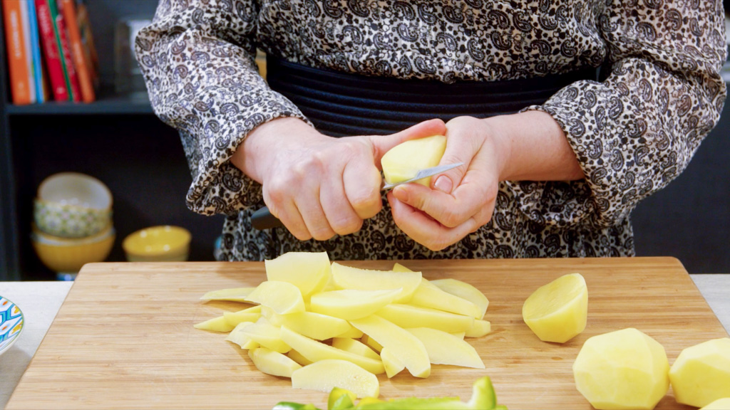 Patate pelate e tagliate in spicchi regolari pronti per la cottura con peperoni