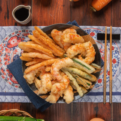 Tempura di gamberi e verdure croccante servita su piatto orientale con bacchette