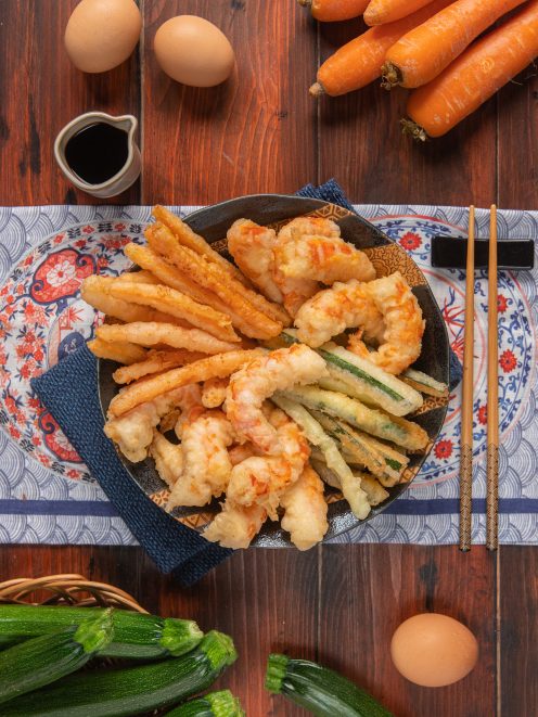 Tempura di gamberi e verdure croccante servita su piatto orientale con bacchette