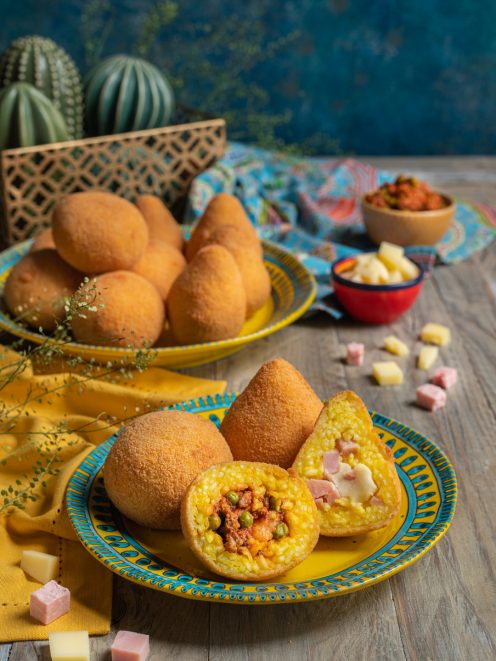 Arancini tagliati a metà che rivelano il ripieno di ragù con piselli e prosciutto con formaggio
