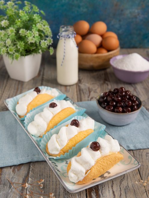 Bocche di leone farcite con panna montata e amarena sciroppata su vassoio decorato