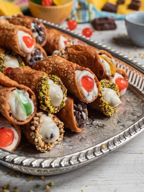 Cannoli siciliani ripieni di ricotta con granella di pistacchio, nocciole, gocce di cioccolato e ciliegie candite