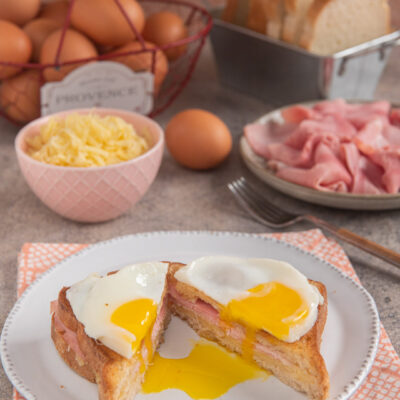 Croque Madame tagliato a metà con tuorlo colante, prosciutto cotto e pane tostato